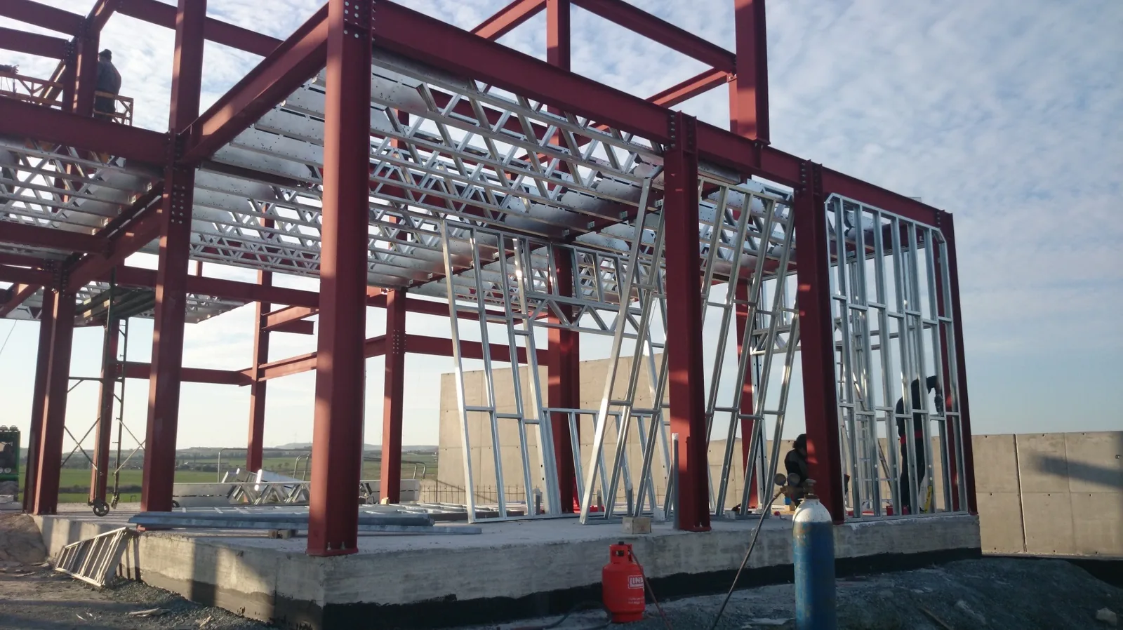 Bolted red steel frame viewed through galvanized partition profiles